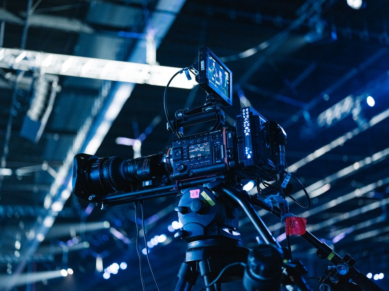 About Close-up of professional video camera setup in a well-lit indoor event venue.